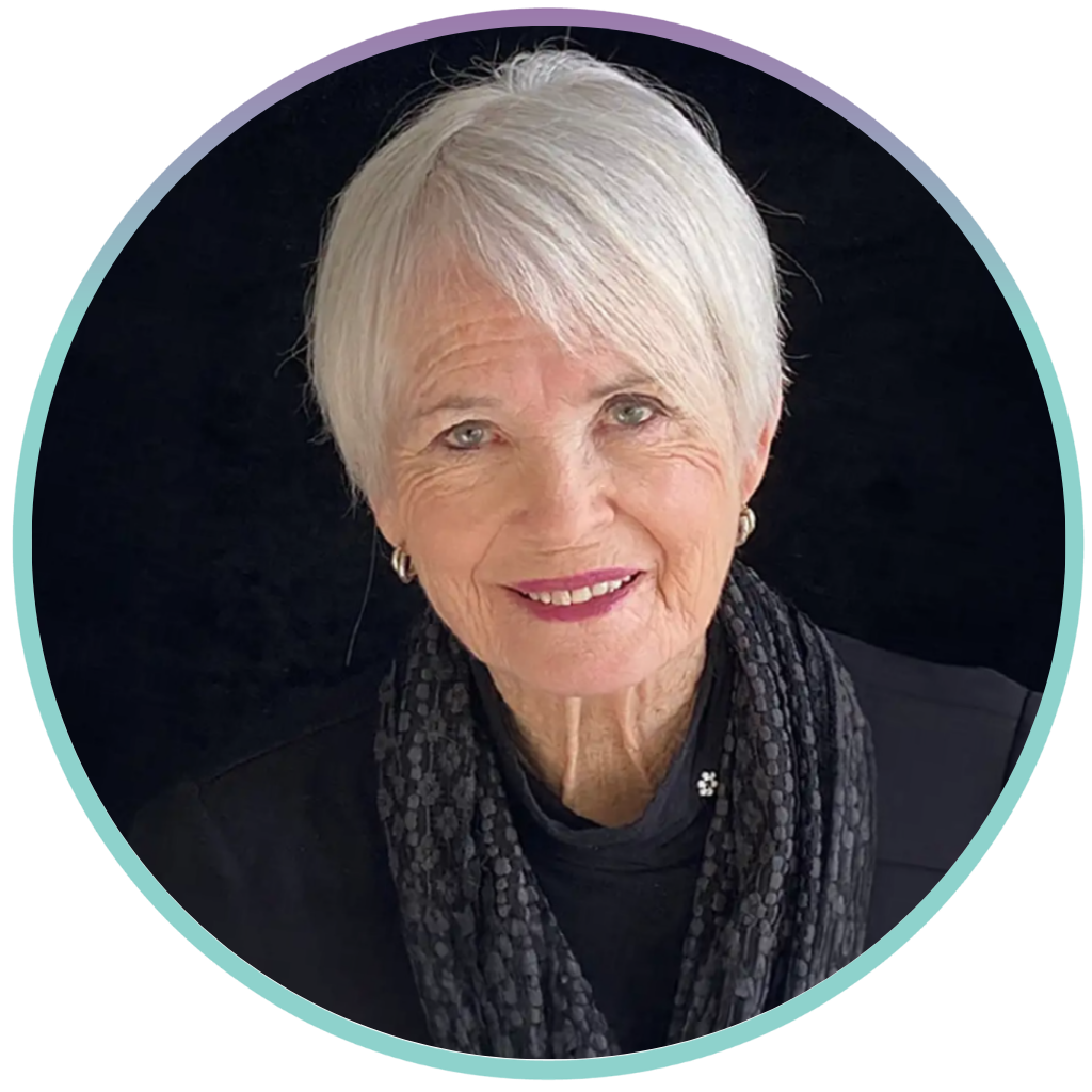 Robin Williams is wearing a black shirt and grey scarf. She has short, white hair and is smiling for a professional photo in front of a black background. There is a blur and purple ring around her photo.