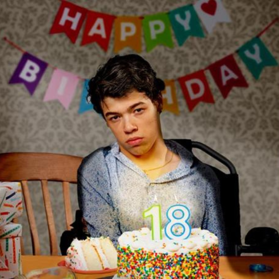 A young man is sitting in his wheelchair while posing for a photo with a serious expression.