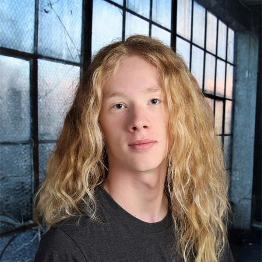 In this professional headshot, William is wearing a black t-shirt. He smiling at the camera in front of a large window. 