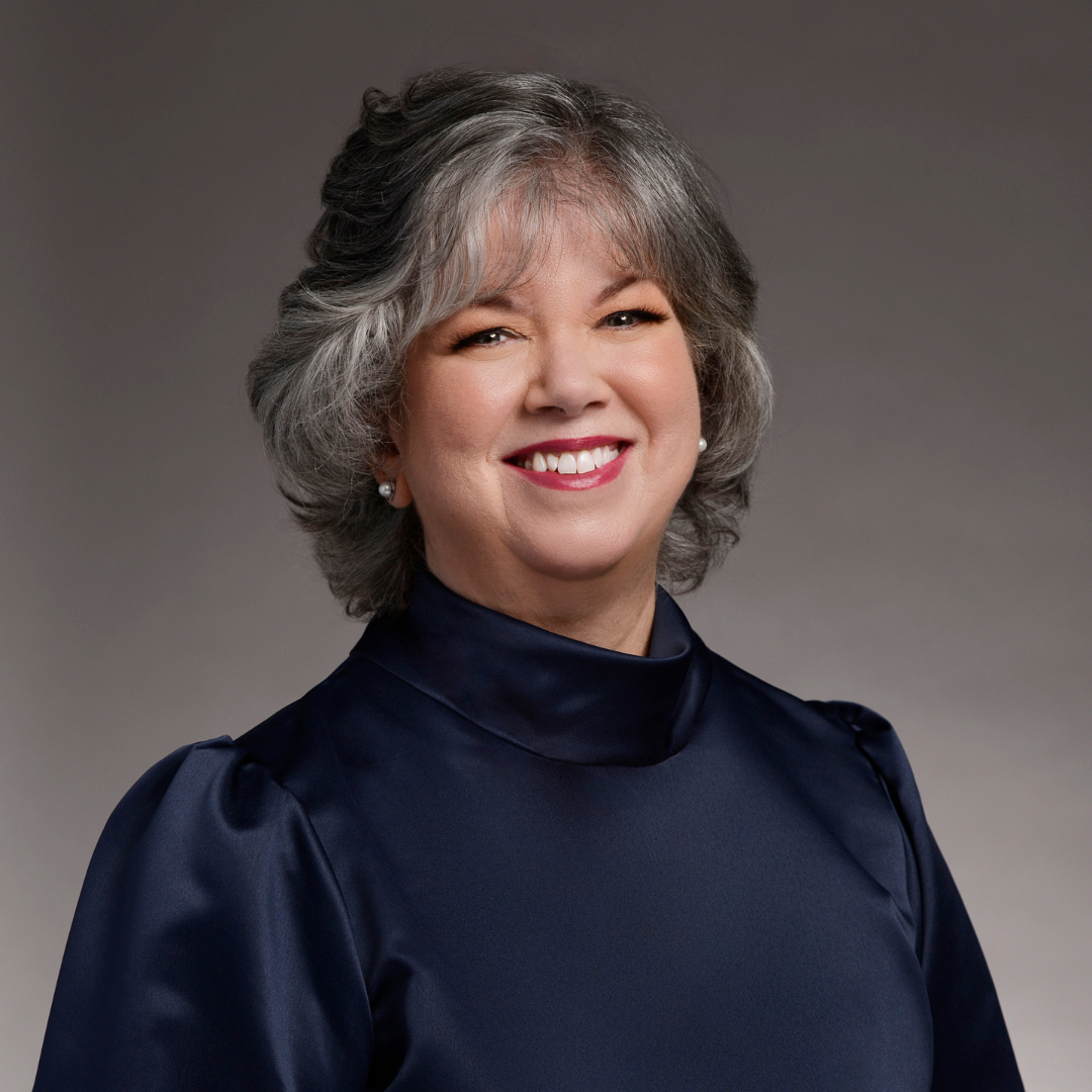 Lorin MacDonald is smiling at the camera. She is wearing a black blouse. The background is a fading grey. 