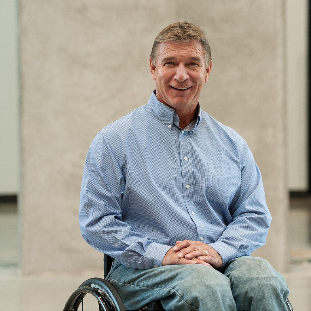 Rick Hansen posing for a professional headshot while sitting in his wheelchair.