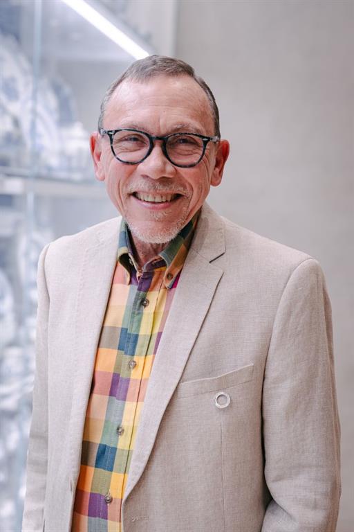 Dr. Garth Smith is wearing a a beige jacket over a colourful plaid shirt and his EKO Tribute Award pinned to his breast pocket.
