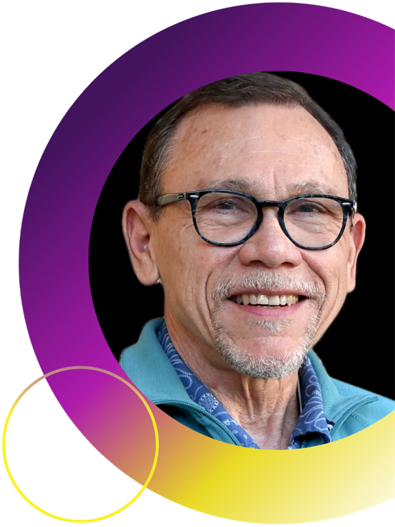 Dr. Garth Smith is wearing a blue collared shirt and has short grey hair and a grey mustache. He is posing for a professional headhsot in front of a black background with a pruple and yellow ring around the image.