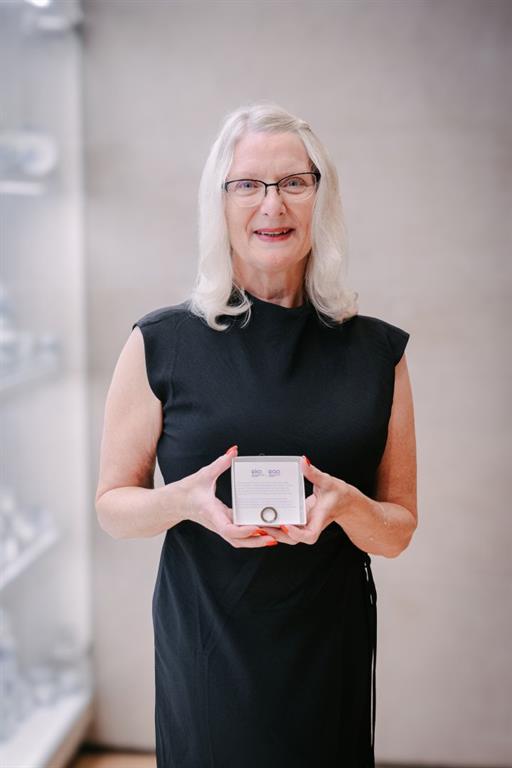 Patty Douglas is pictured in a black dress holding her EKO Tribute Award pin in its box.