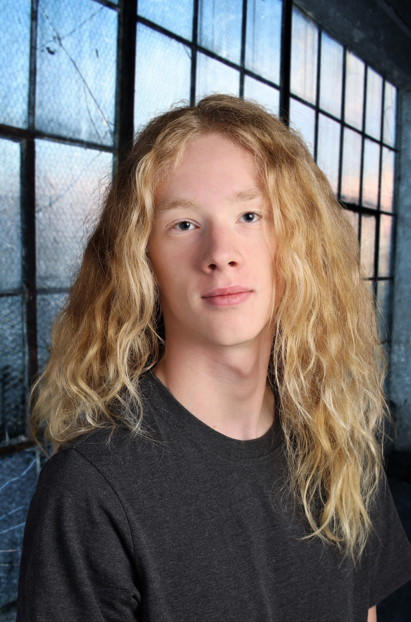 In this professional headshot, William is wearing a black t-shirt. He is smiling at the camera in front of a large window. 